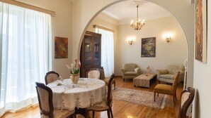 A dining area with a round table, chairs, a chandelier, and artwork on the walls. - Classic Central Athinian Apartment (Athens)