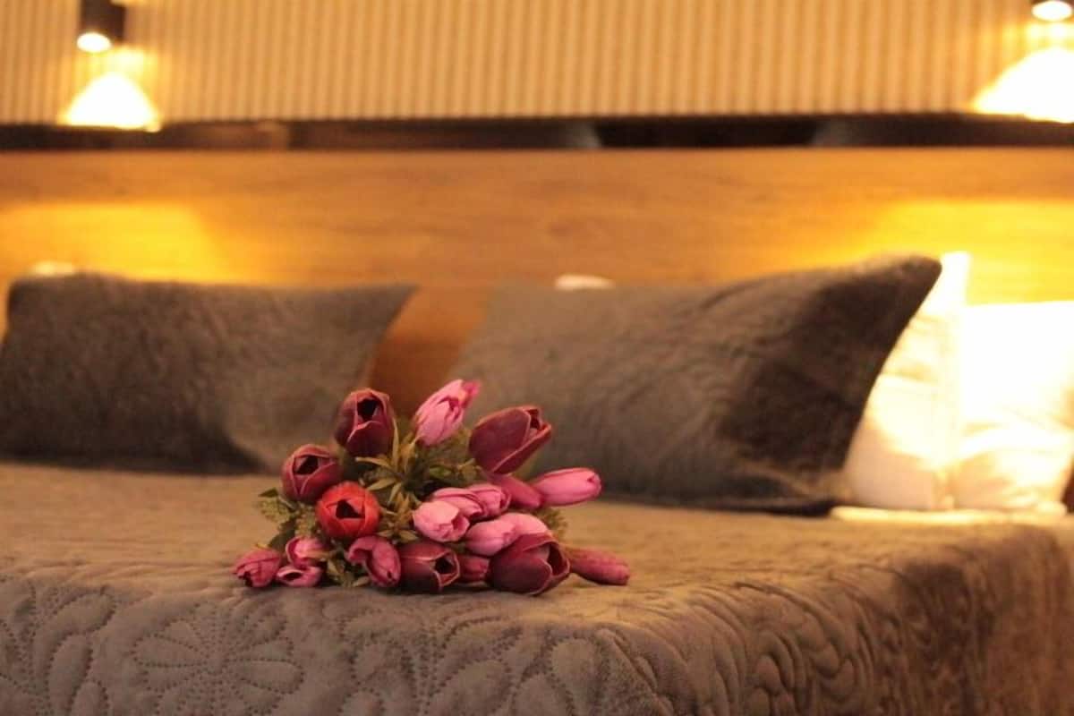 Una cama con un edredón texturizado y un ramo de flores rosas en el centro.