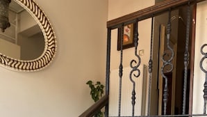Un escalier orné de balustres noirs et d’une main courante blanche, menant à un palier agrémenté d’un miroir et d’un tableau encadré.