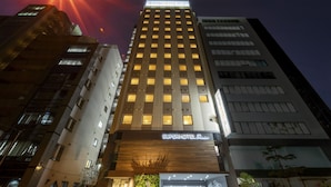 A SuperHotel Premier building with a modern facade, illuminated windows, and a prominent entrance.