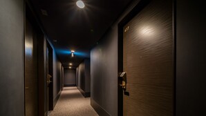 A corridor with dark walls, a carpeted floor, and doors on both sides.