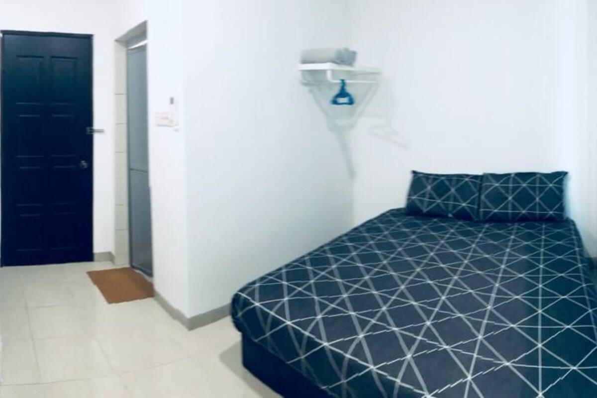 Una stanza piccola e pulita con un letto, una porta e una mensola fissata al muro.