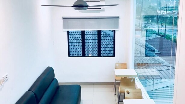A modern waiting area with a black sofa, wooden chairs, a ceiling fan, and a large window with a view of palm trees. - Luna Stay by Yolodge (Lunas)