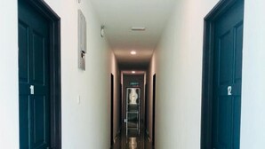 A long, narrow hallway with dark wooden doors on either side, numbered 11 and 12, leading to a central elevator. - Luna Stay by Yolodge (Lunas)
