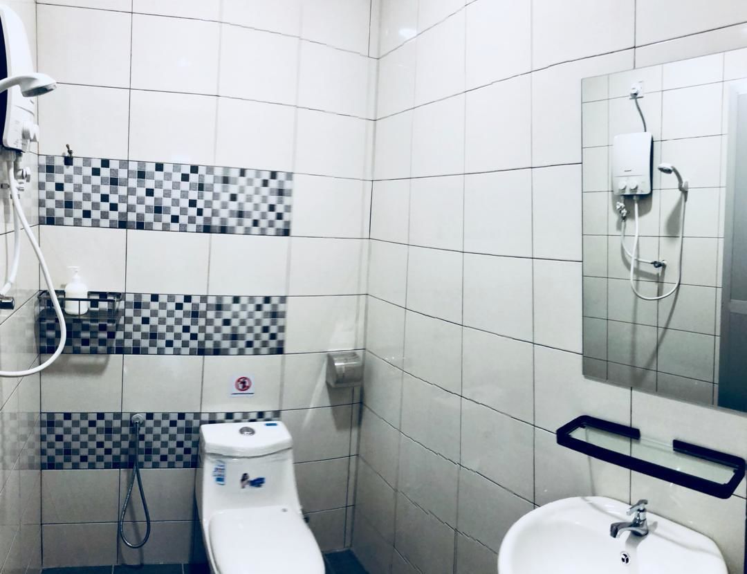 A small bathroom with white tiles, a toilet, a sink, a shower, and a mirror.