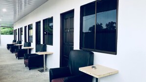 A row of black leather chairs with small tables, white walls, and large windows. - Luna Stay by Yolodge (Lunas)