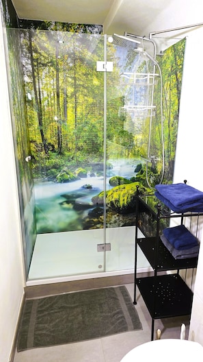 A shower with a forest mural, a towel rack, and a small shelf. - Altes Zollhaus (Ammeldingen an der Our)