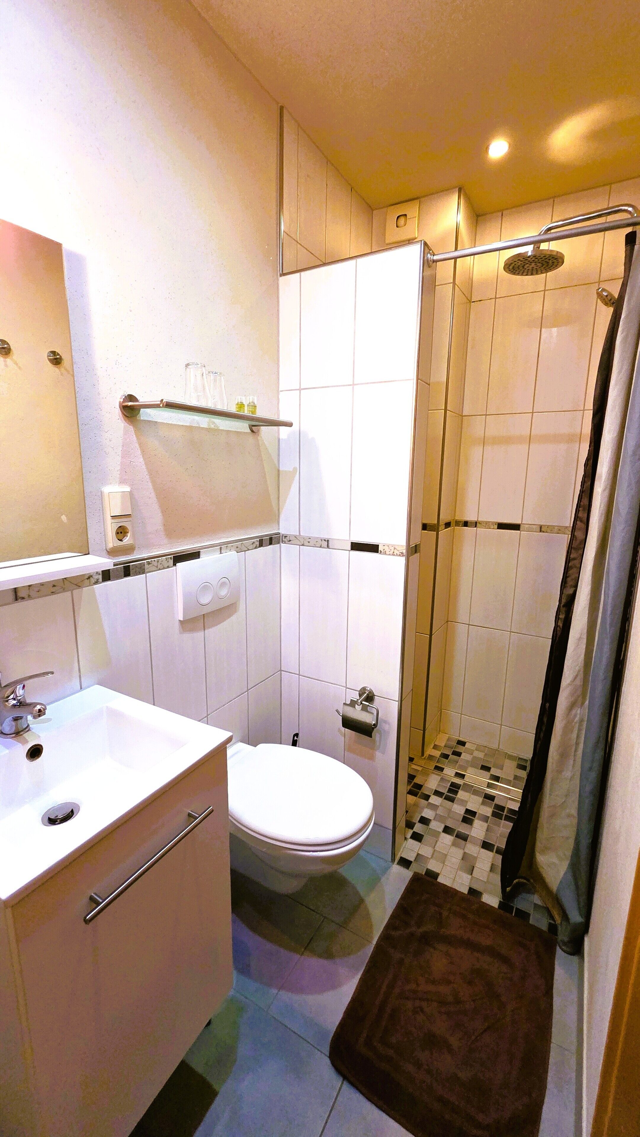 Een badkamer met een wastafel, toilet, douche en spiegel.