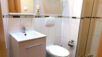 Un baño con lavamanos blanco, inodoro y cabina de ducha de vidrio.