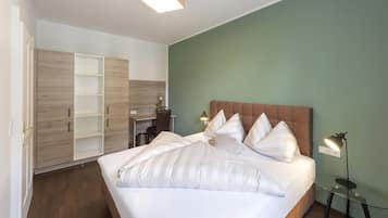 A bedroom with a large bed, a desk, and a wardrobe.