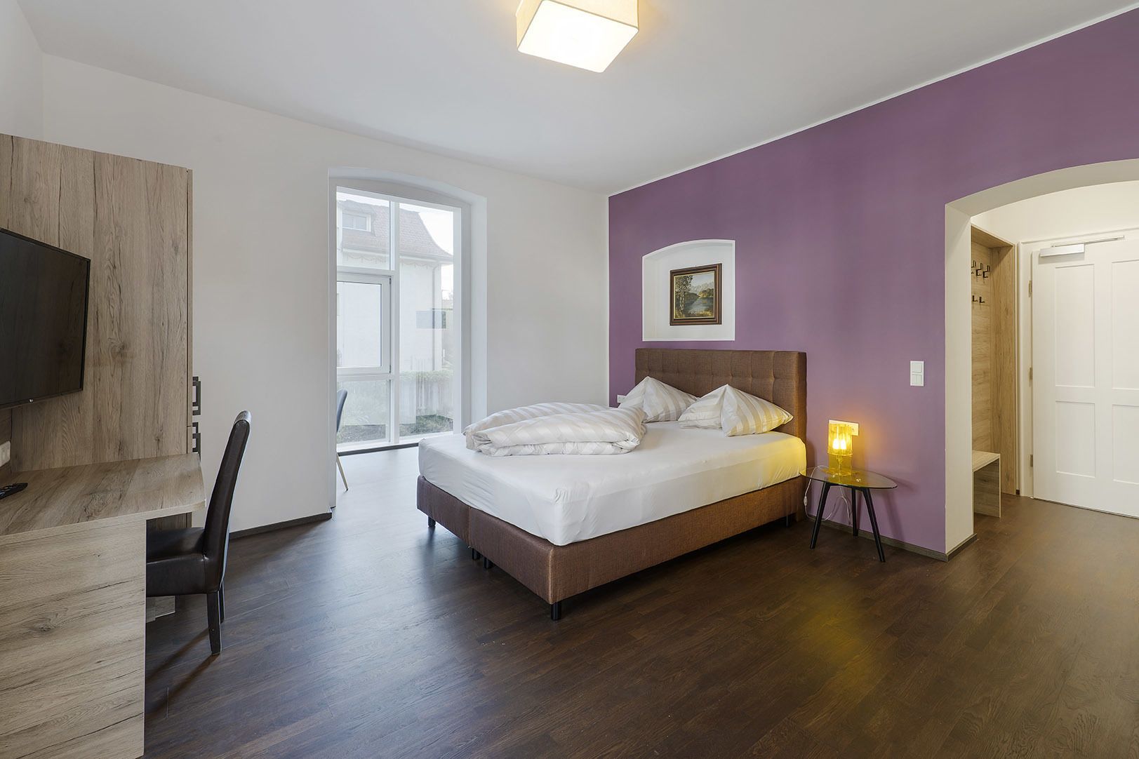 Een slaapkamer met een bed, een bureau, een stoel en een televisie.