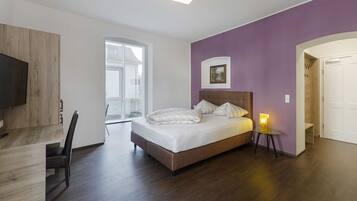 Een slaapkamer met een bed, een bureau, een stoel en een televisie.