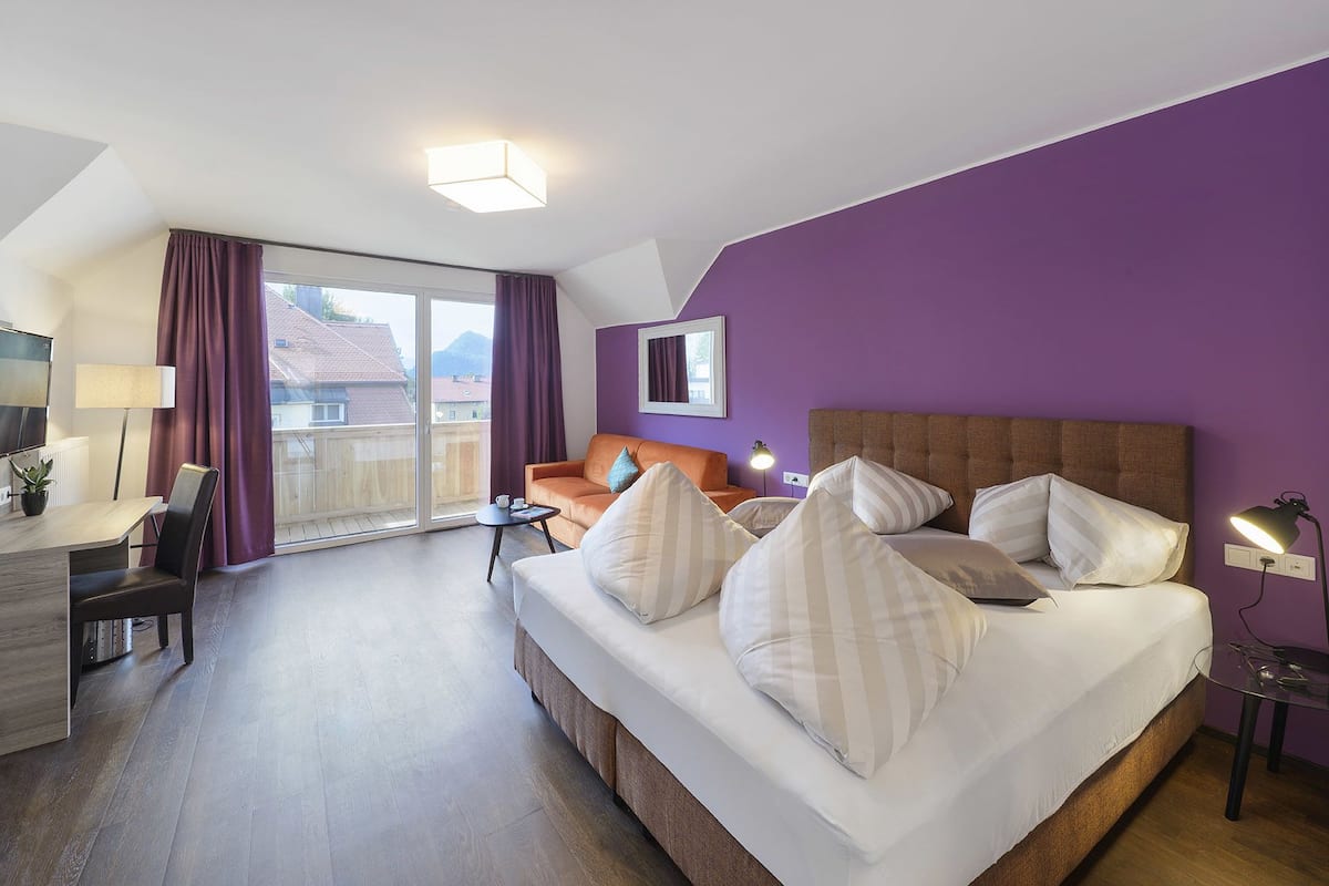 Une chambre d’hôtel équipée d’un lit, d’un bureau, d’une chaise, d’une table et offrant une vue sur l’extérieur.