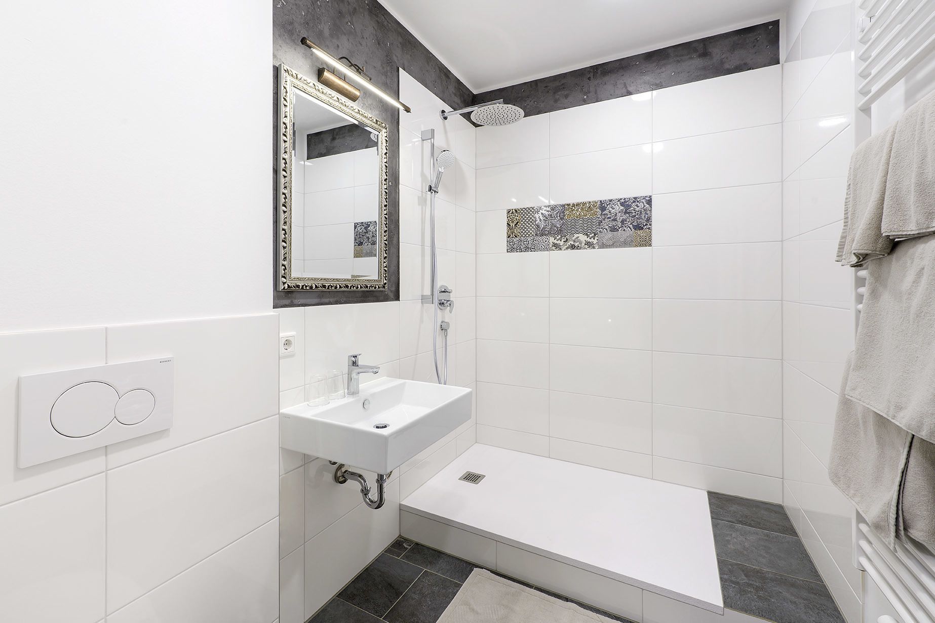 Un baño moderno con lavamanos, espejo y ducha blancos.