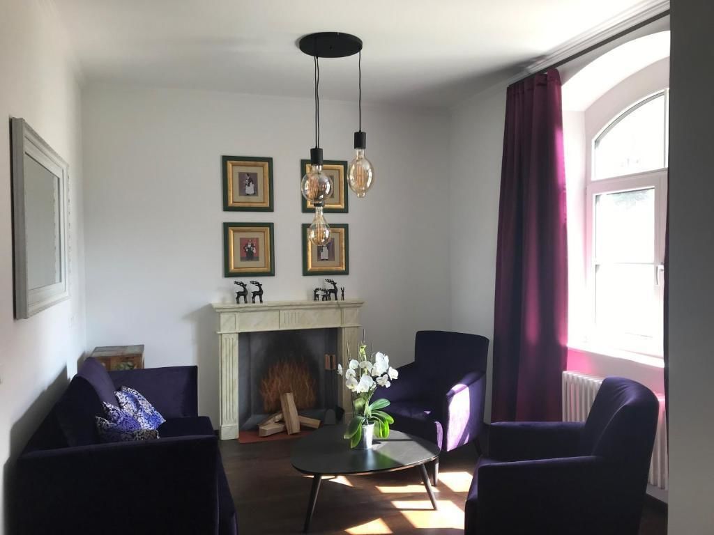 A living room with a fireplace, two armchairs, a coffee table, and a chandelier.