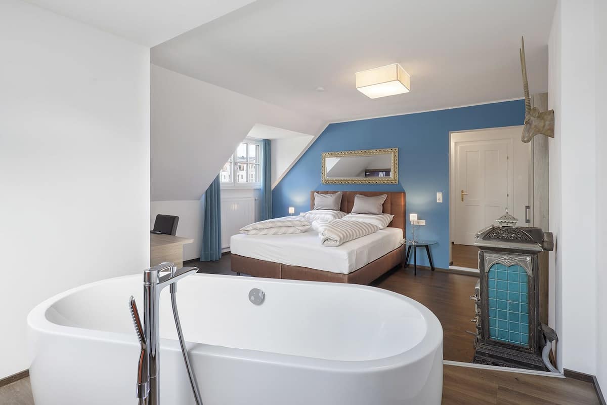 Une chambre moderne avec un grand lit, un coin salon et une baignoire.