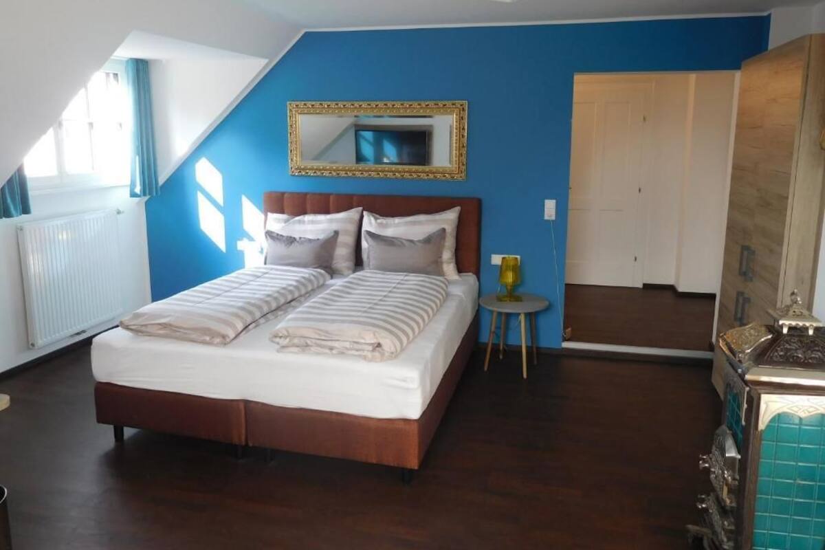 Une chambre à coucher avec un lit, une petite table, un miroir et une armoire.