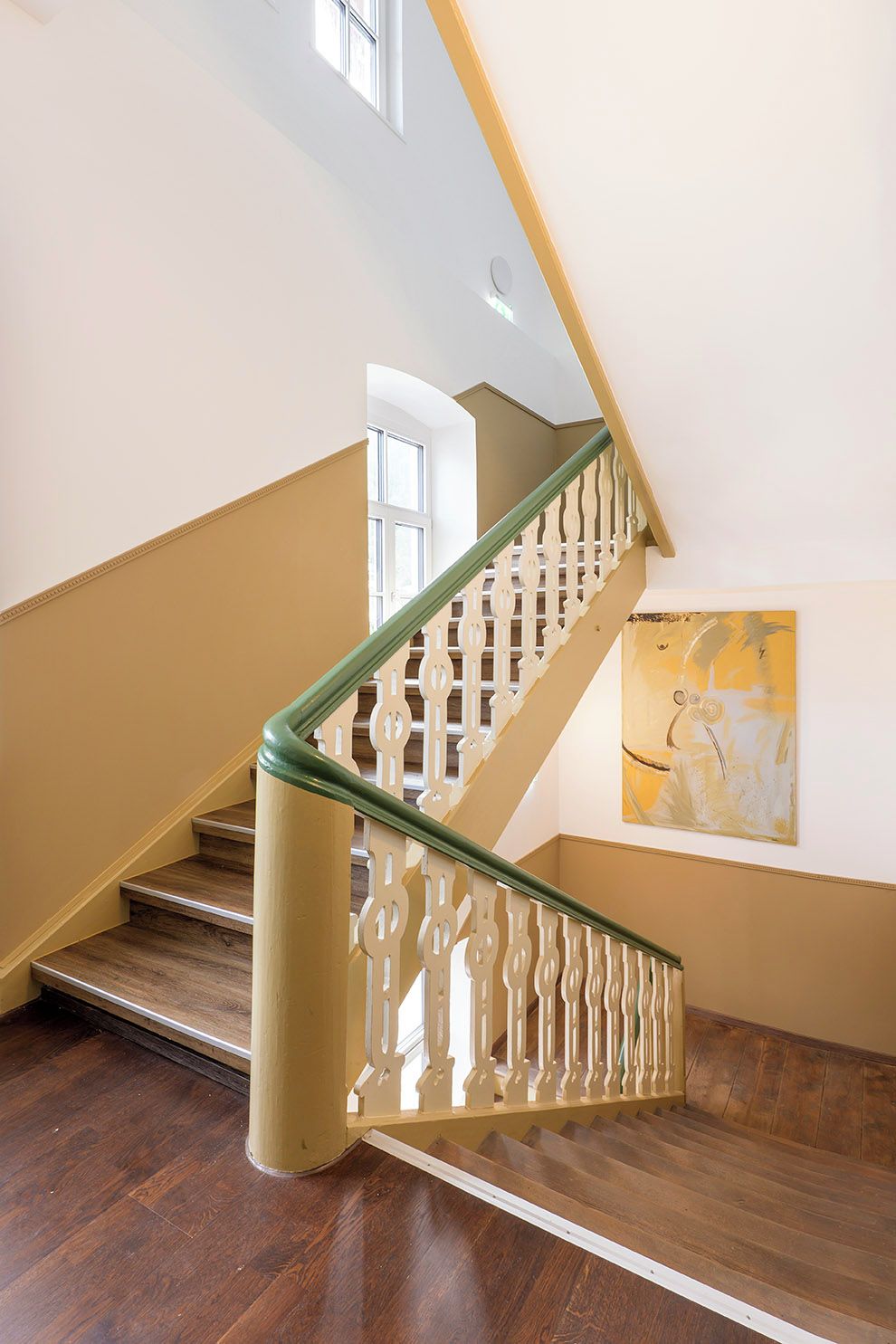 Un escalier avec une rampe en bois et un mur de couleur beige.