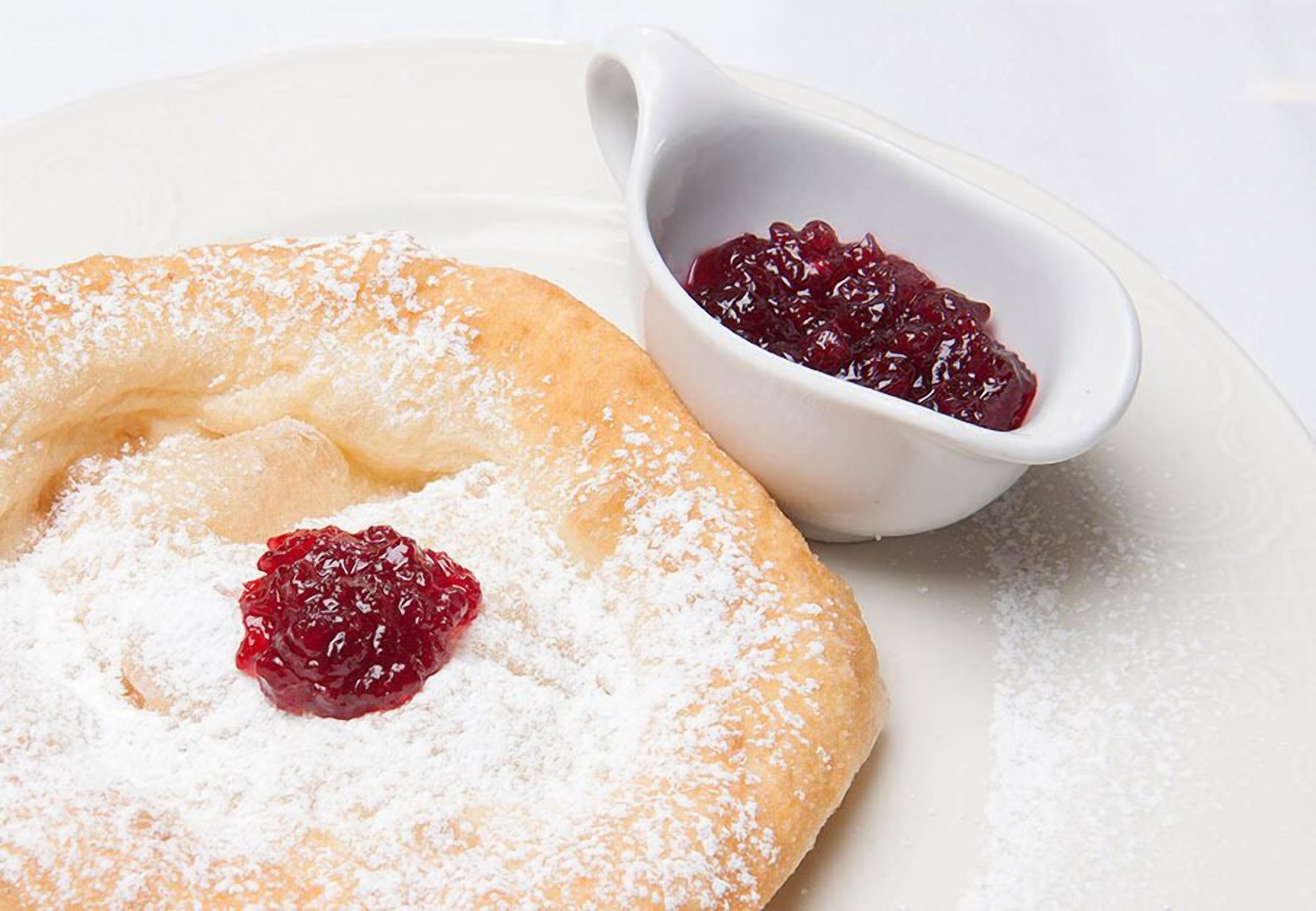 Un postre con azúcar glas y un pequeño bol de compota de frutos rojos.