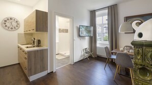 A modern kitchen with wooden cabinets, a built-in sink, and a clock. There is a dining area with a table, chairs, and a decorative lamp. - Villa Maria - Suiten & Appartements (Kufstein)