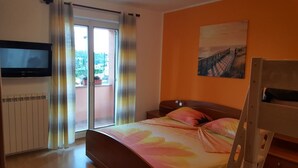 A bedroom with a bed, a TV mounted on the wall, a painting, and a balcony with curtains. - Apartment Kalin (Piran)