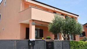 A two-story building with a peach-colored facade, a balcony, and a tree in front. - Apartment Kalin (Piran)