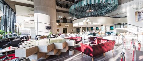 A spacious lobby with a central seating area, a high ceiling, and a modern chandelier.