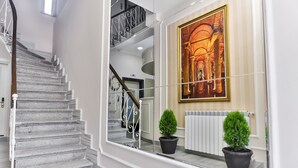 A staircase with a railing, a potted plant, and a framed picture on the wall.