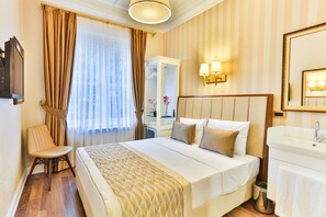 A hotel room with a bed, a chair, a desk, a mirror, and a bathroom. - Hanende Hotel (Istanbul)