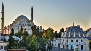 A historic building with multiple domes and minarets, surrounded by trees and other structures.