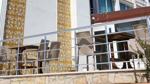 Un hotel de varios pisos con una fachada llamativa en dorado y blanco, que presenta un patrón vertical dorado y el nombre "ANEMONA" en el lateral.