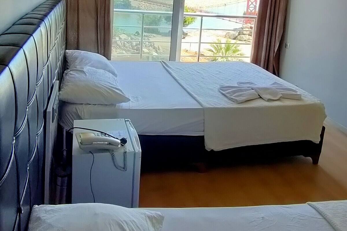A hotel room with two beds, a hairdryer, a lamp, and a view of a bridge and landscape.