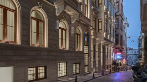 Un edificio storico dall'architettura elaborata, con ampie finestre e una strada acciottolata.