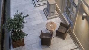 Una terrazza esterna con zona salotto, gradini che conducono a un balcone e un parapetto decorativo.