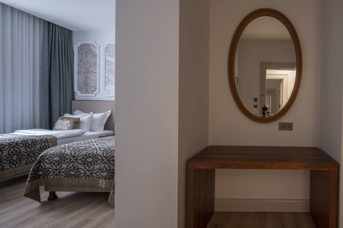 A hotel room with two beds, a wooden console table, and a large mirror on the wall.