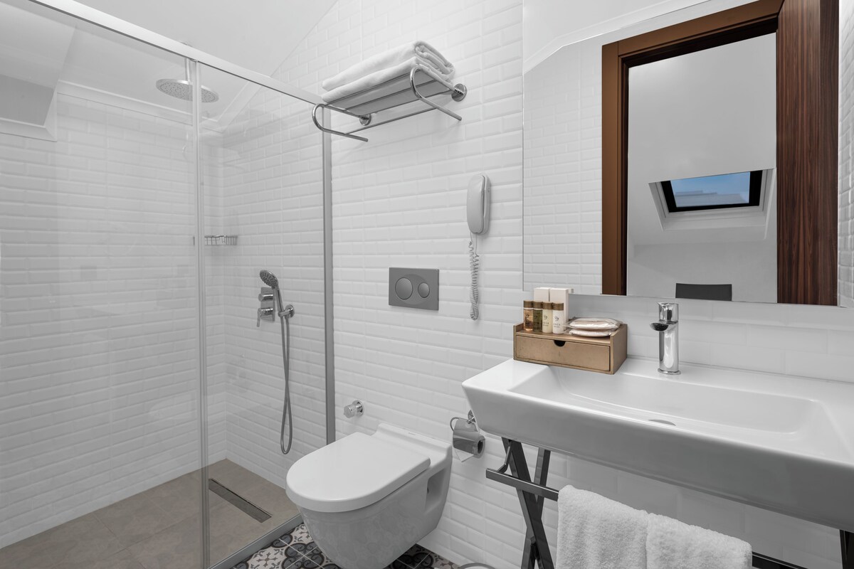 A modern bathroom with a glass shower enclosure, a toilet, a sink with a mirror, and a towel rack.