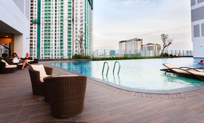 A rooftop pool area with lounge chairs and a view of high-rise buildings.