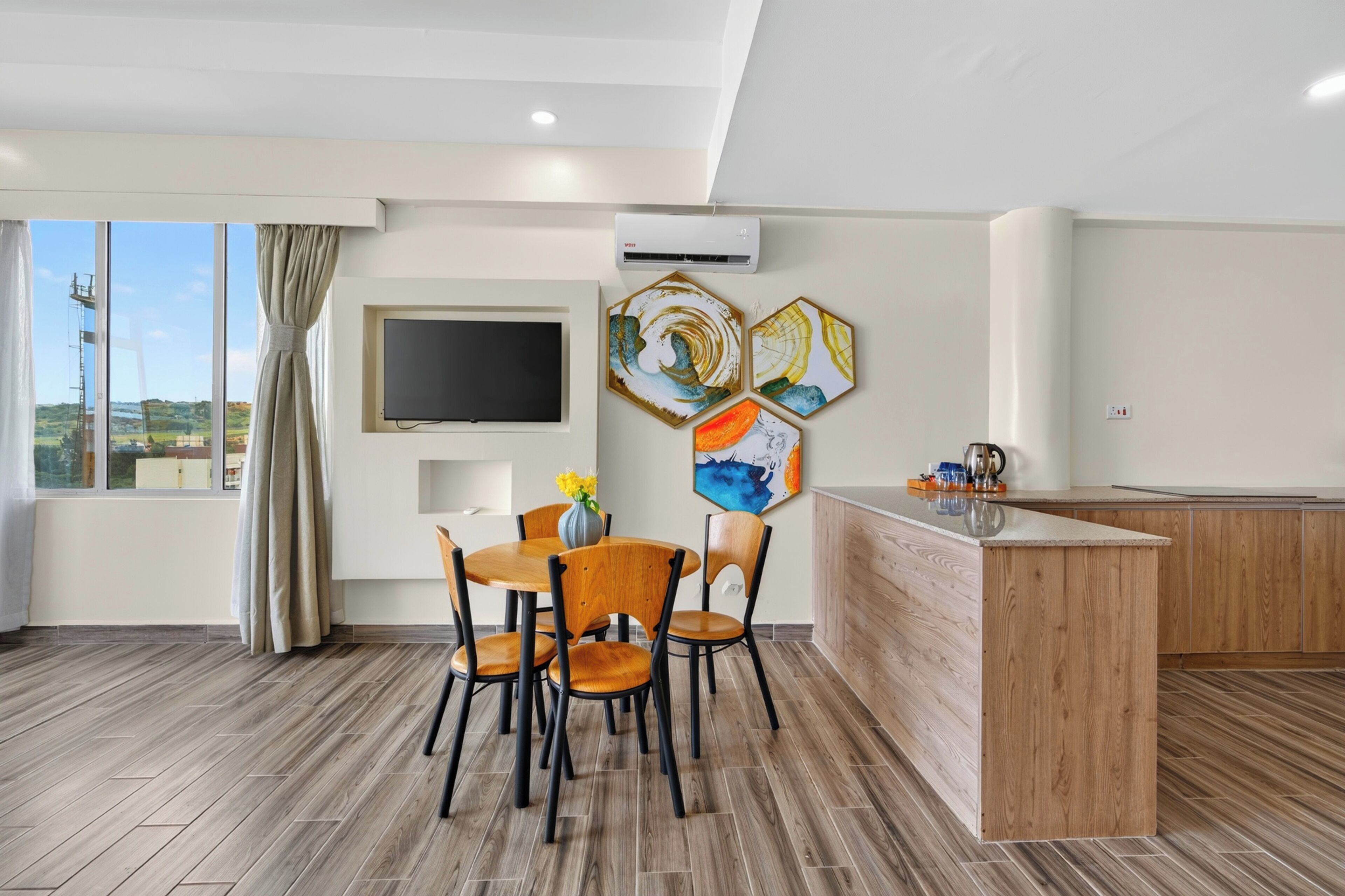 Una cocina moderna con encimera de madera, un comedor con mesa y sillas, y un ventanal con cortinas.