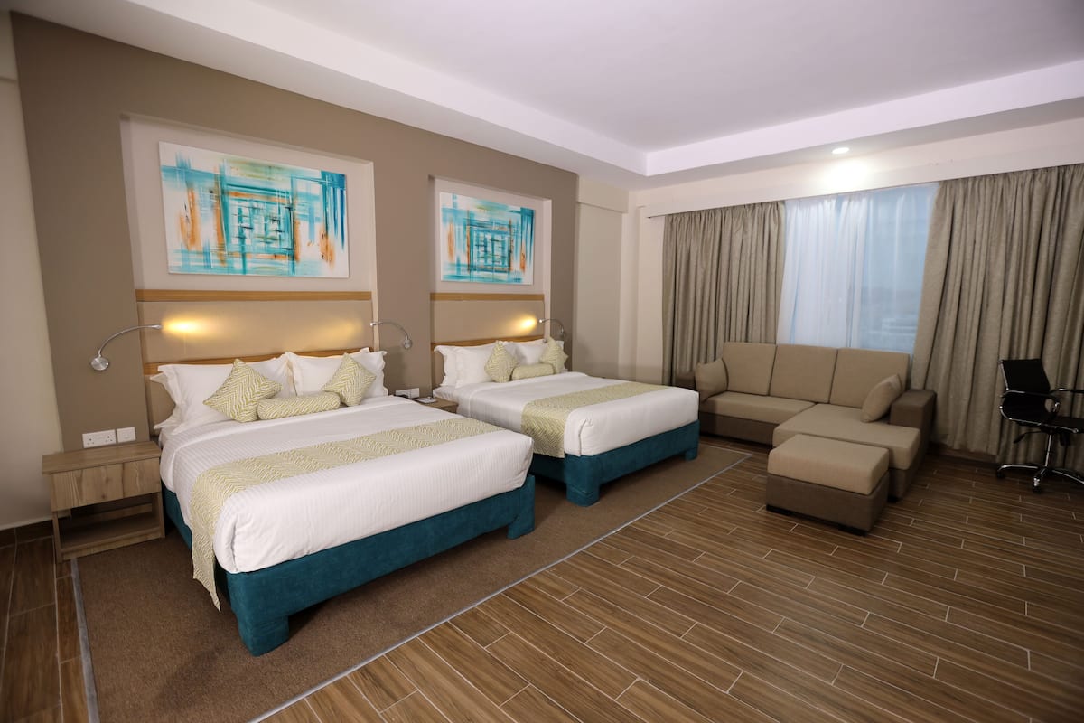 Une chambre d’hôtel avec deux lits, un canapé, un bureau et une chaise.