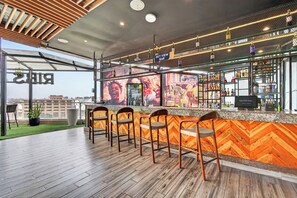 A bar area with a herringbone wood wall, bar stools, and a view of the cityscape. - PrideInn Plaza Nairobi Airport (Mlolongo)