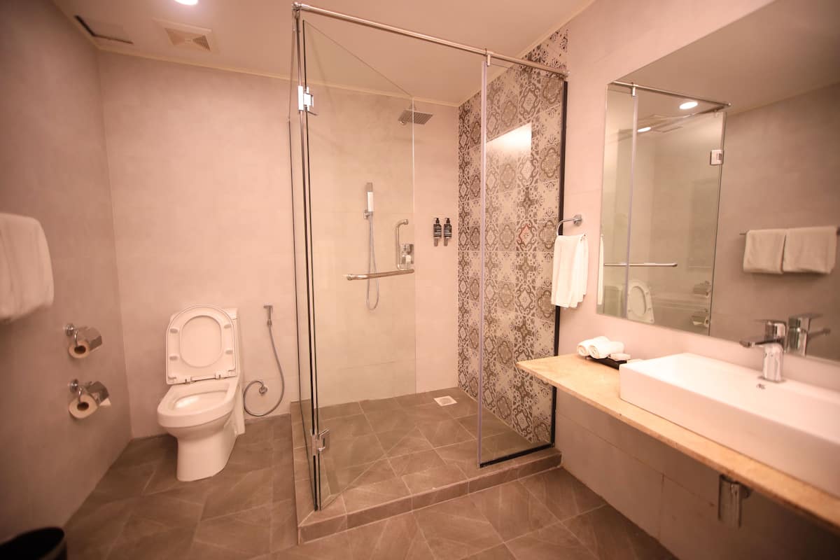 Un baño moderno con ducha acristalada, inodoro blanco y un espejo grande sobre un lavamanos.