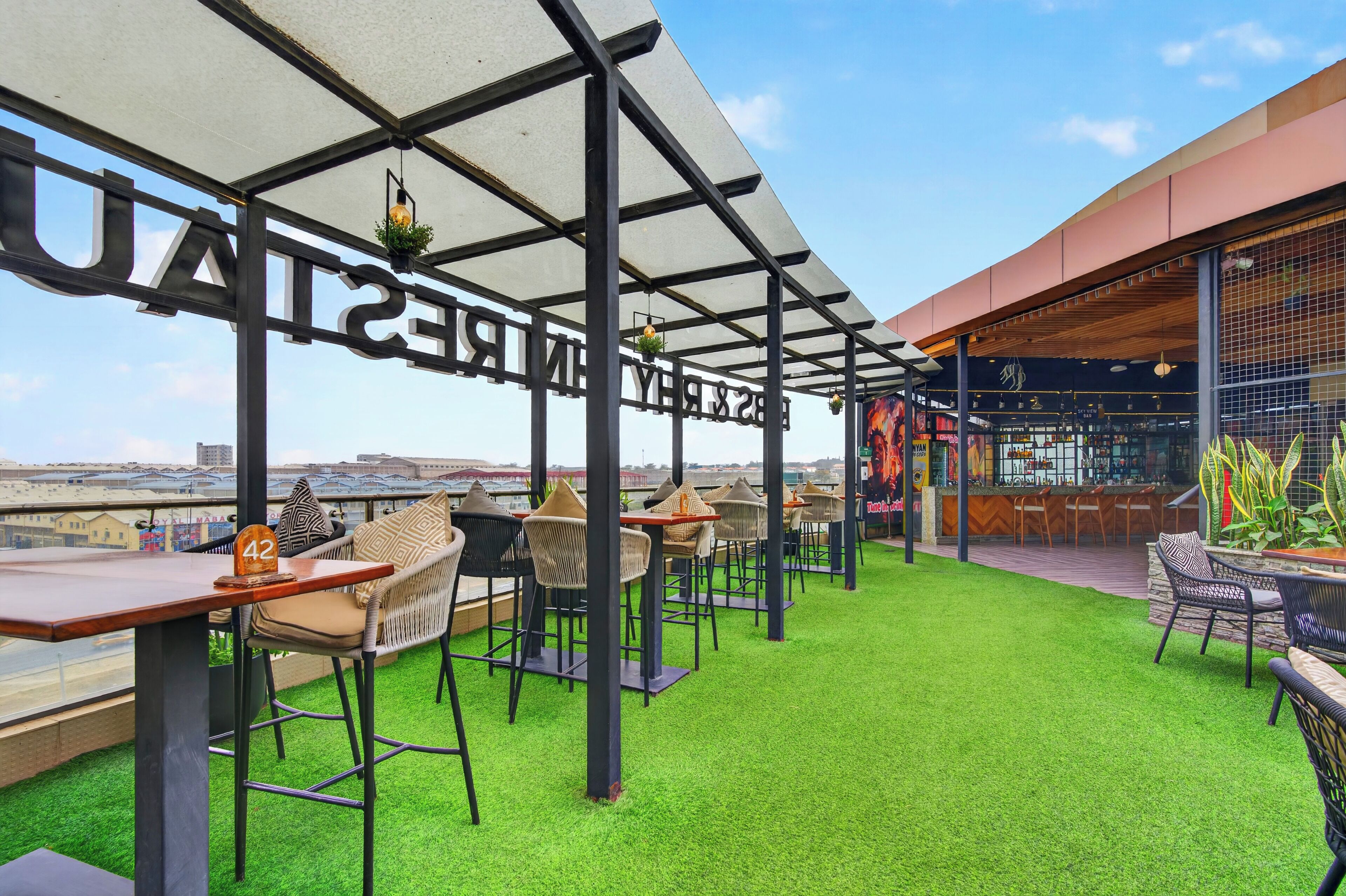 An outdoor seating area with a view of the city skyline, featuring a bar and a restaurant with a modern design.
