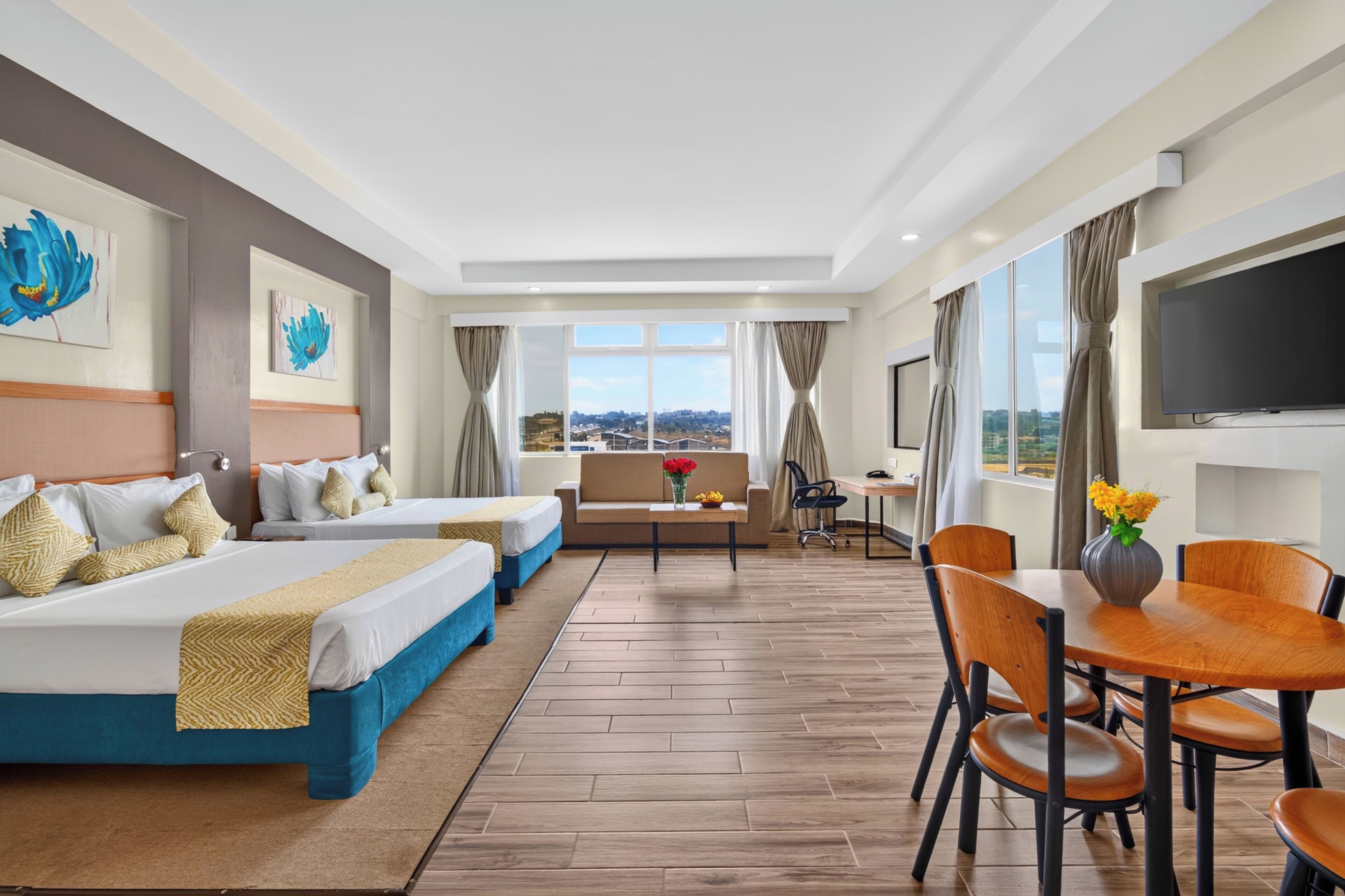 Habitación de hotel con una cama grande, un sofá, una mesa de comedor y un televisor.