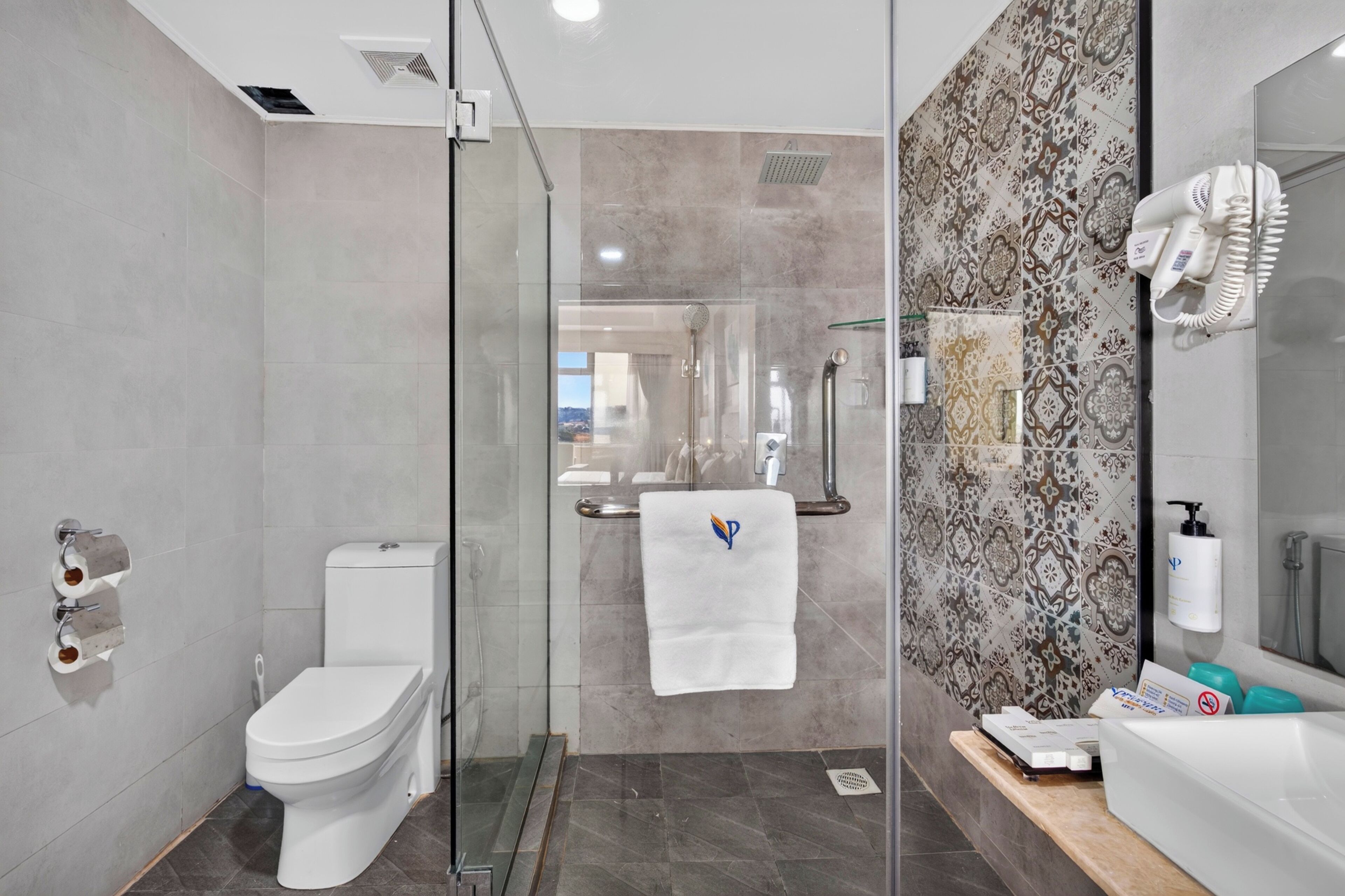 Un baño moderno con inodoro, ducha y zona de ducha con mampara de vidrio.