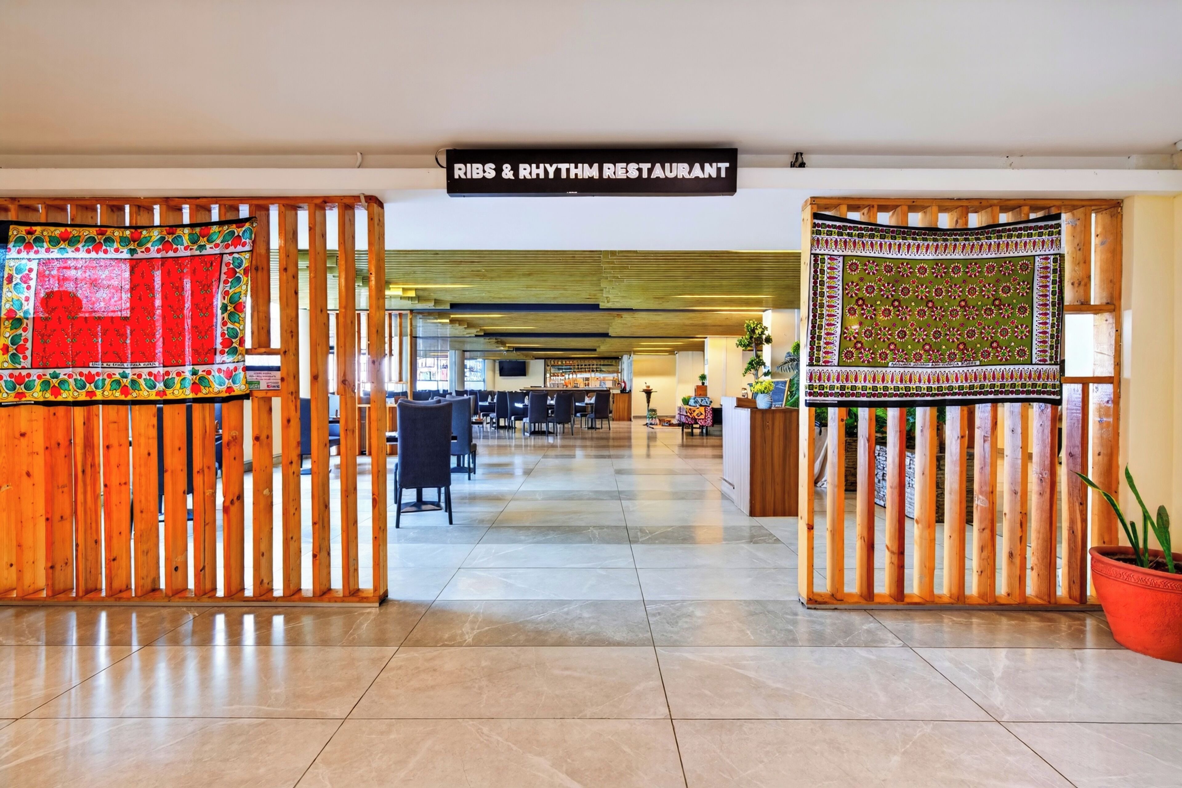 Entrada a un restaurante con un letrero que dice 'RIBS & RHYTHM RESTAURANT' y una decoración textil colorida en la puerta de madera.