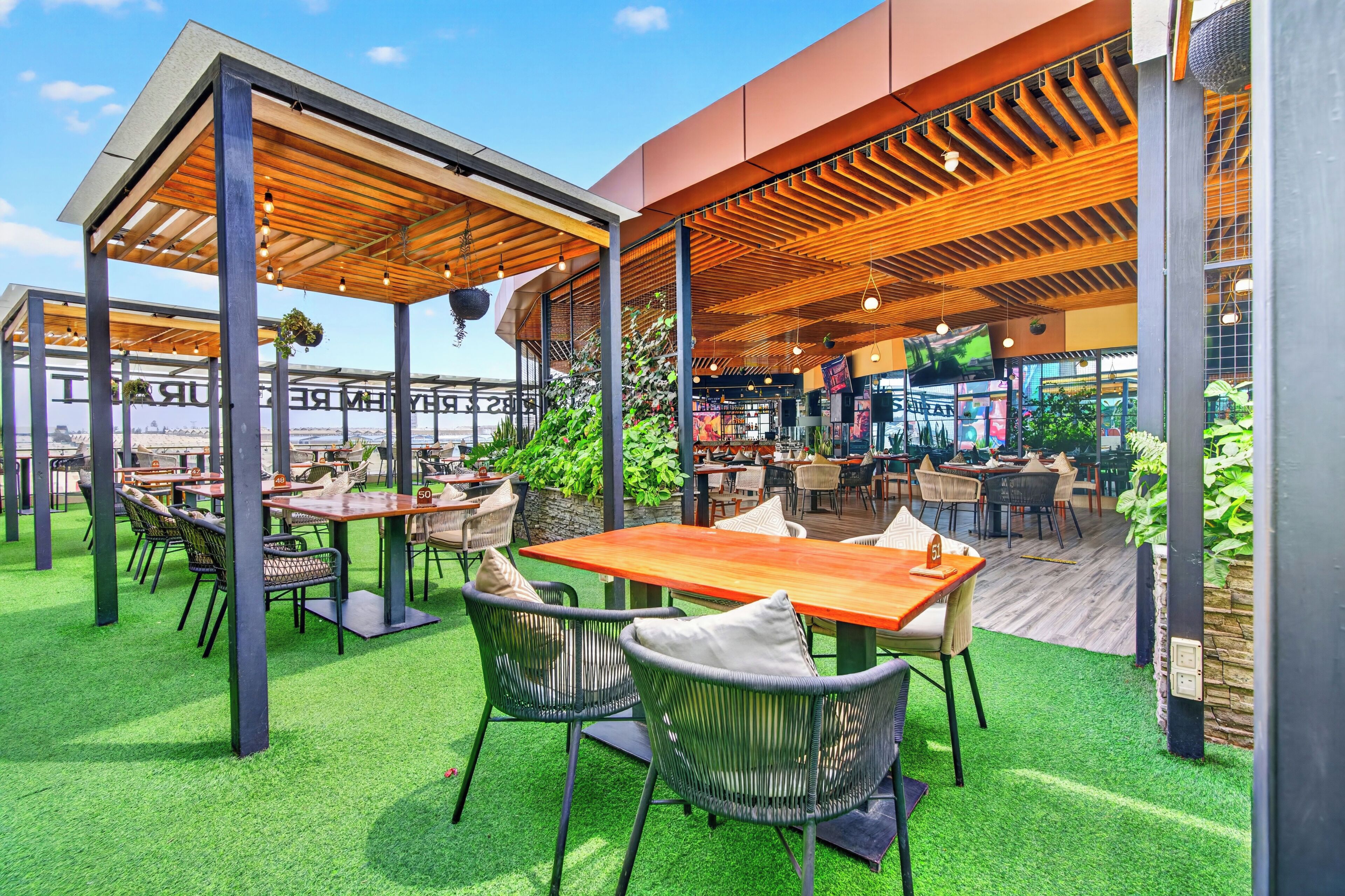 Un espace extérieur aménagé avec des tables et des chaises, une pergola en bois et une vue sur le paysage urbain.