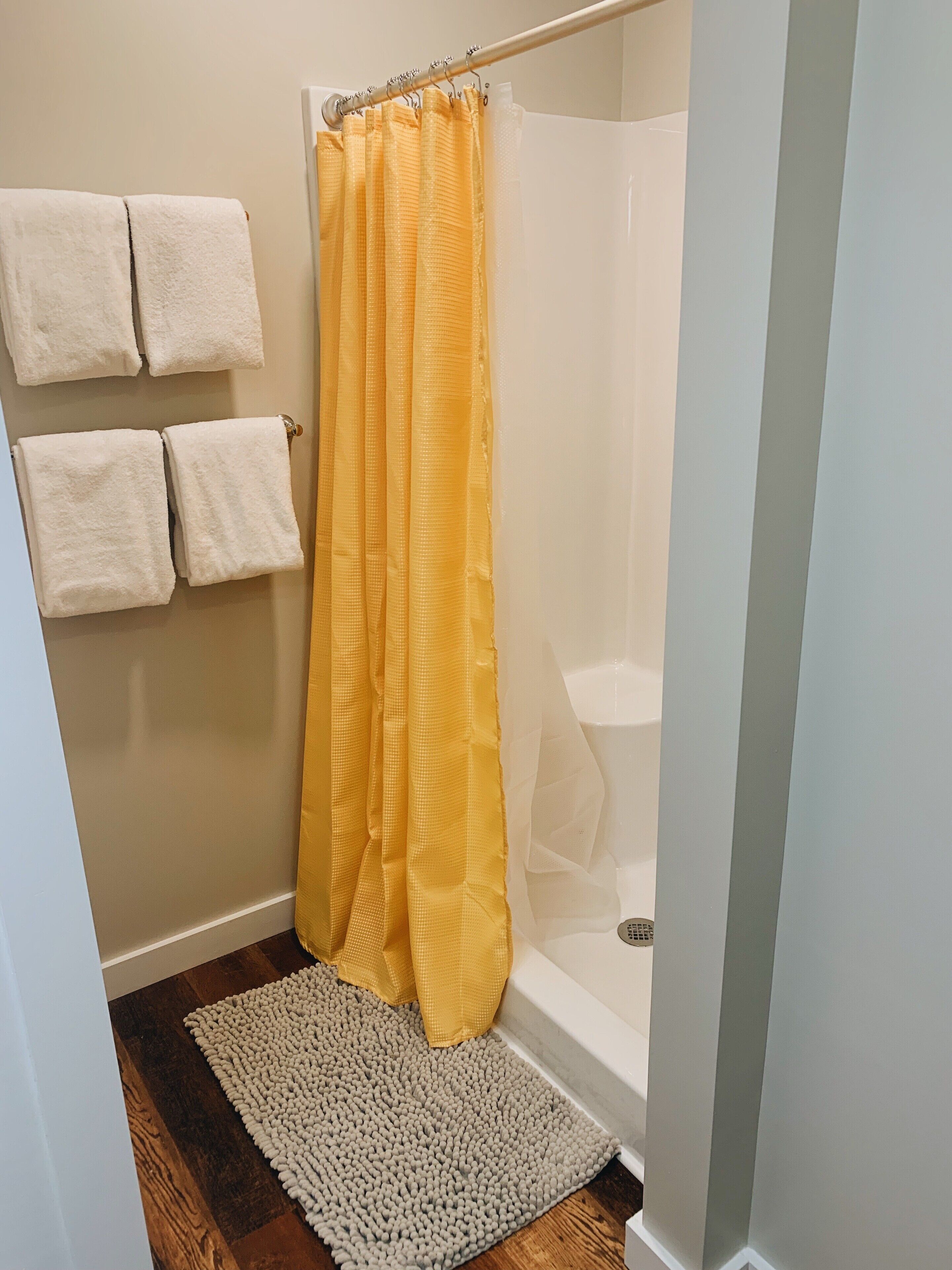 A bathroom with a shower curtain, a bathtub, and a rug.