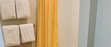 A bathroom with a shower curtain, a bathtub, and a rug.