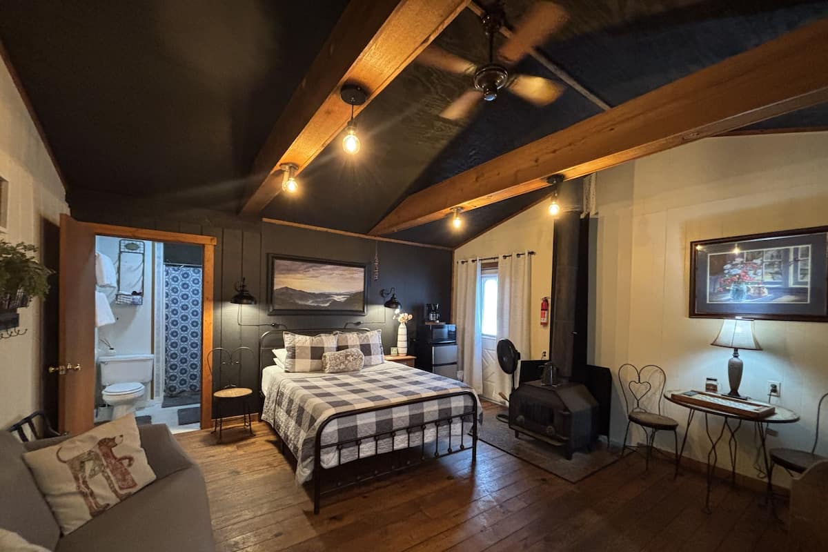 Ein gemütliches Schlafzimmer mit Bett, Schreibtisch, Stuhl, Kamin und angrenzendem Badezimmer.