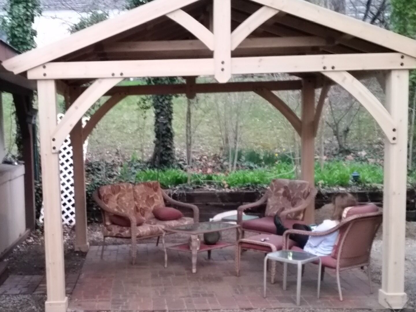 Un belvédère en bois doté d’un patio couvert, aménagé avec deux chaises et une petite table.